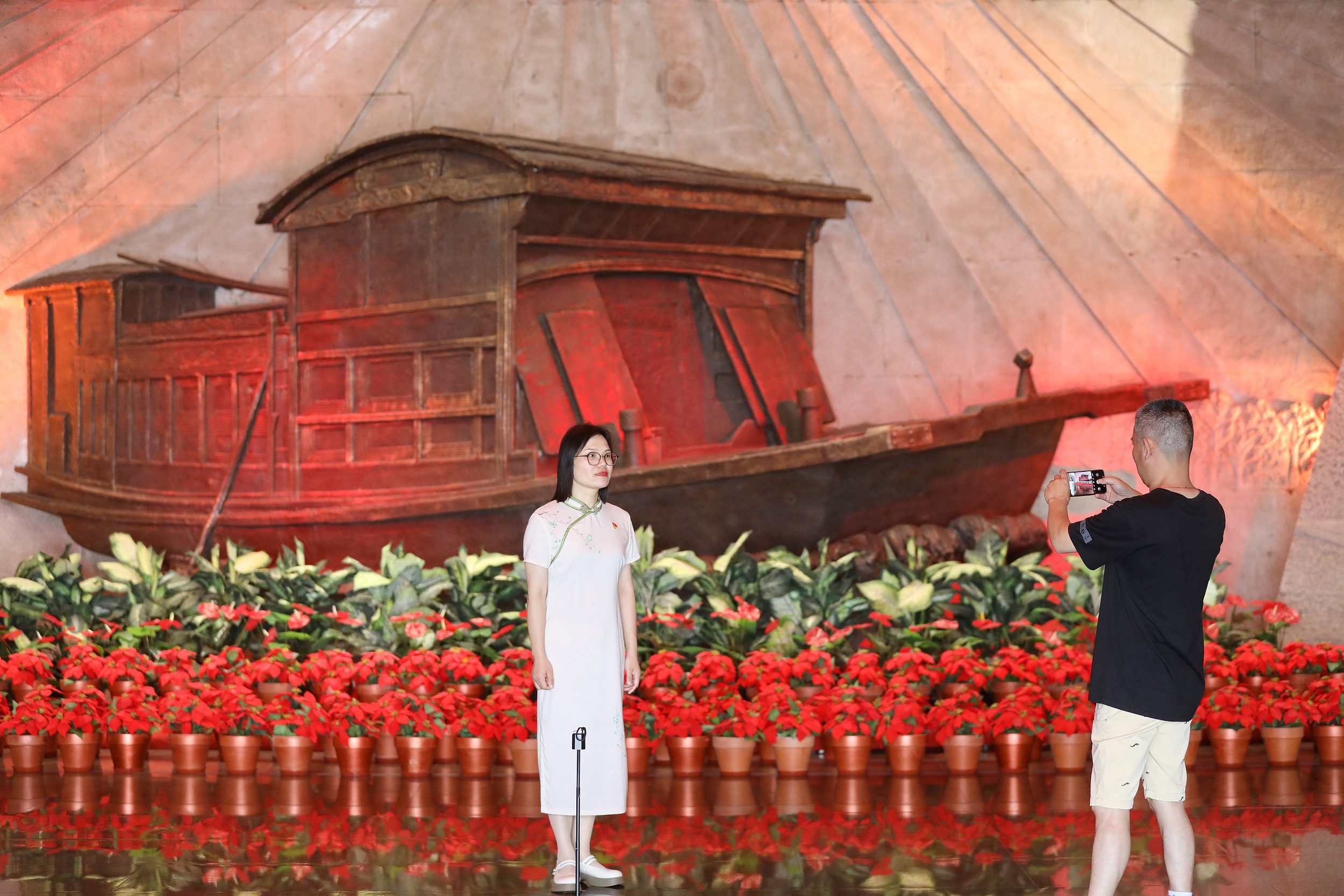 2025年6月24日，浙江嘉興，游客在南湖革命紀(jì)念館與紅船雕塑合影。（圖片來源：視覺中國）